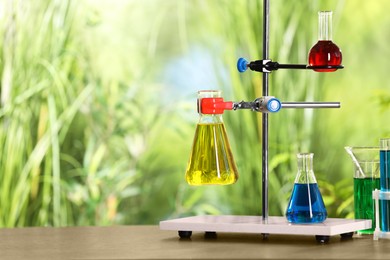 Laboratory glassware with colorful liquids on table against blurred background. Space for text