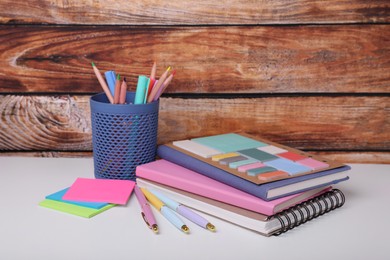 Different school stationery on white table near wooden wall. Back to school