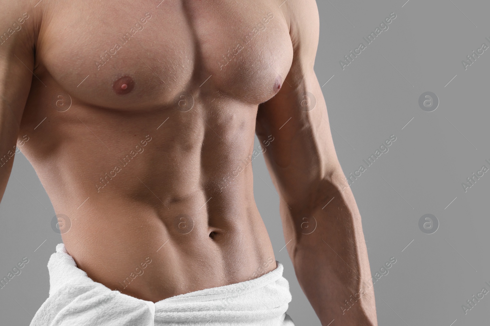 Photo of Muscular man showing abs on grey background, closeup