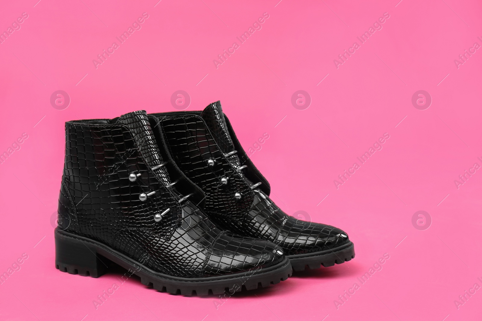 Photo of Pair of stylish ankle boots on pink background