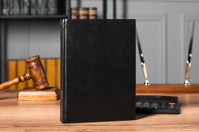Photo of Tax law. Book, calculator and gavel on wooden table