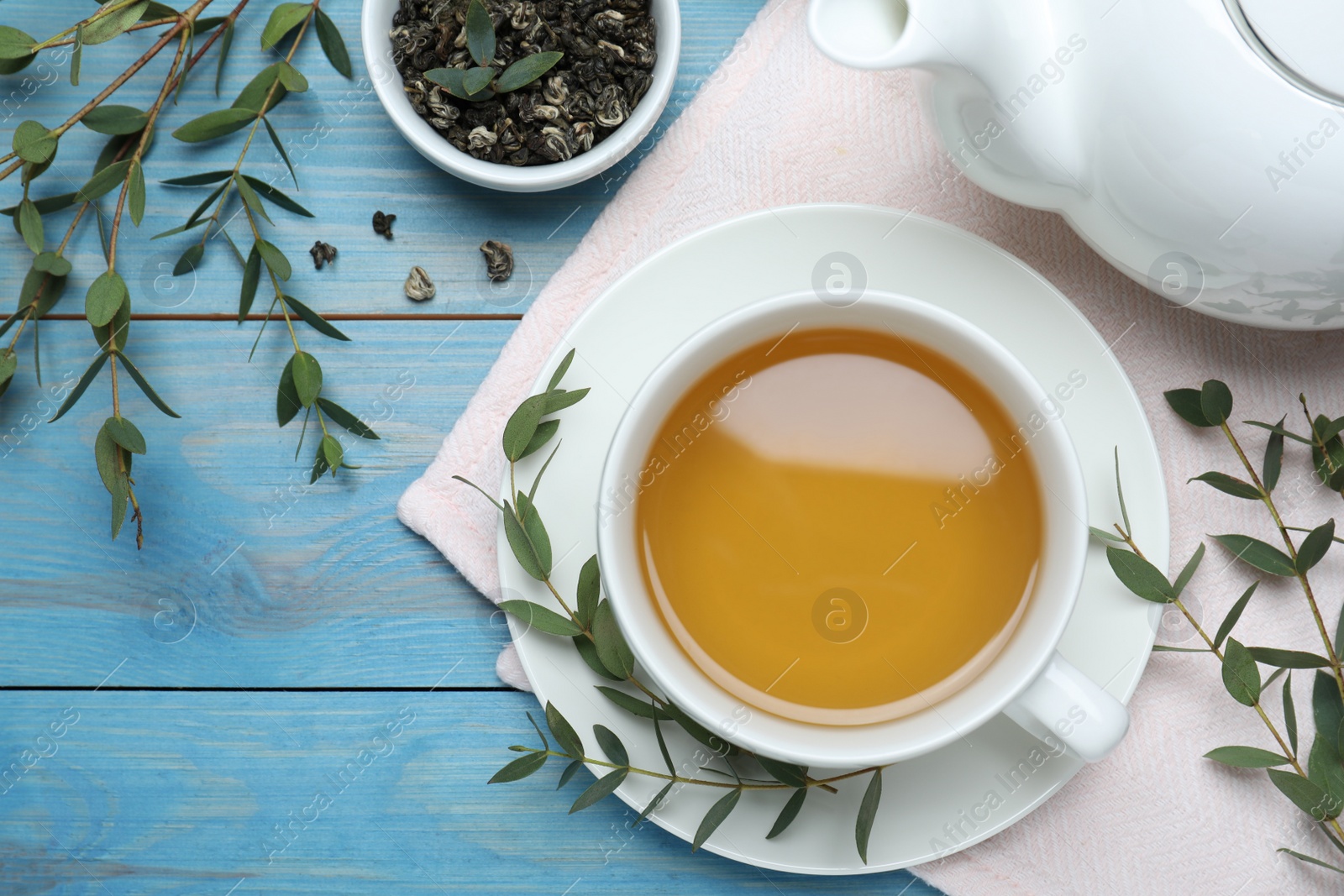 Photo of Aromatic eucalyptus tea on light blue wooden table, flat lay