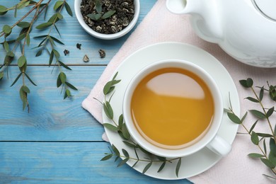 Photo of Aromatic eucalyptus tea on light blue wooden table, flat lay