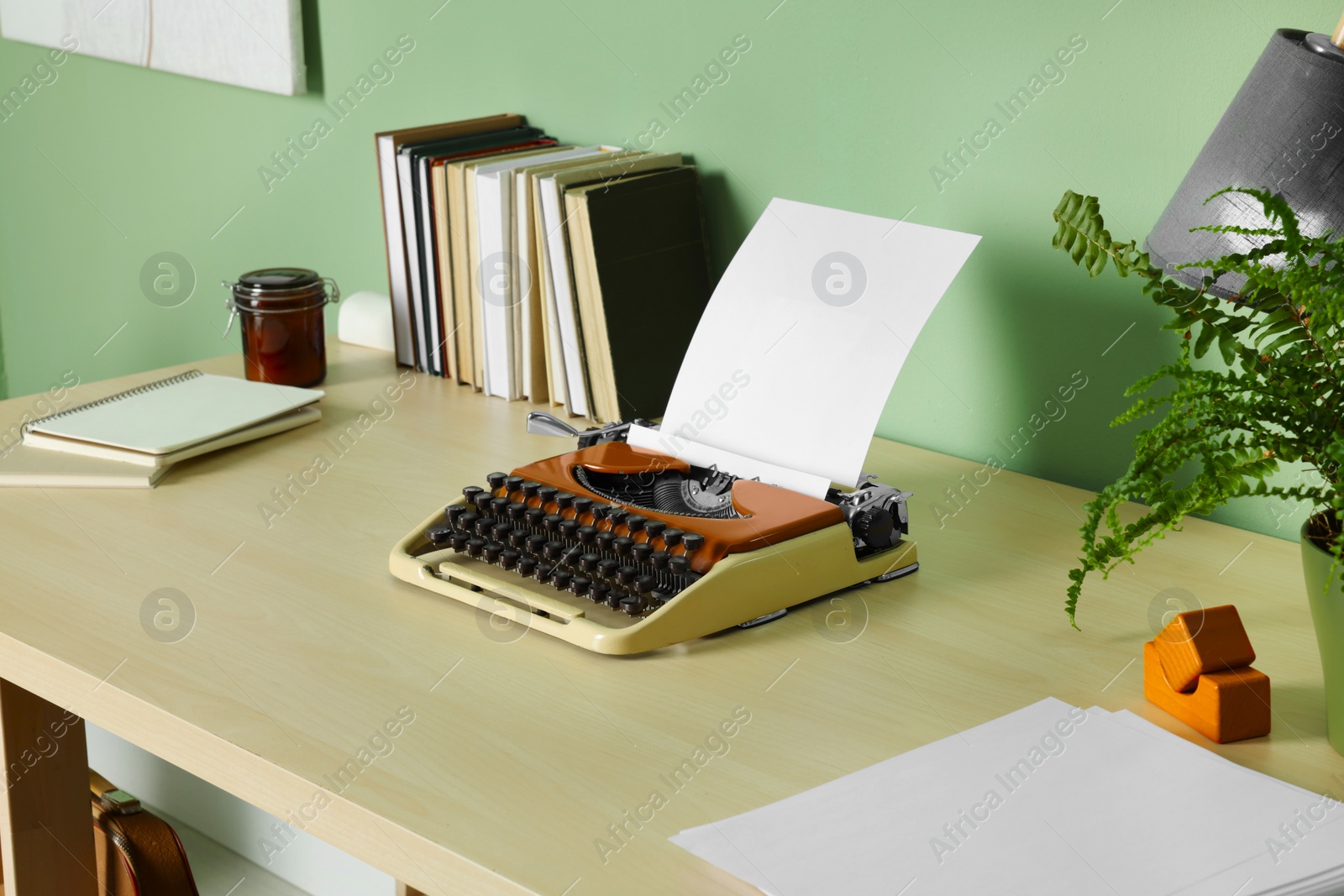 Photo of Writer's workplace with typewriter on wooden desk near pale green wall in room