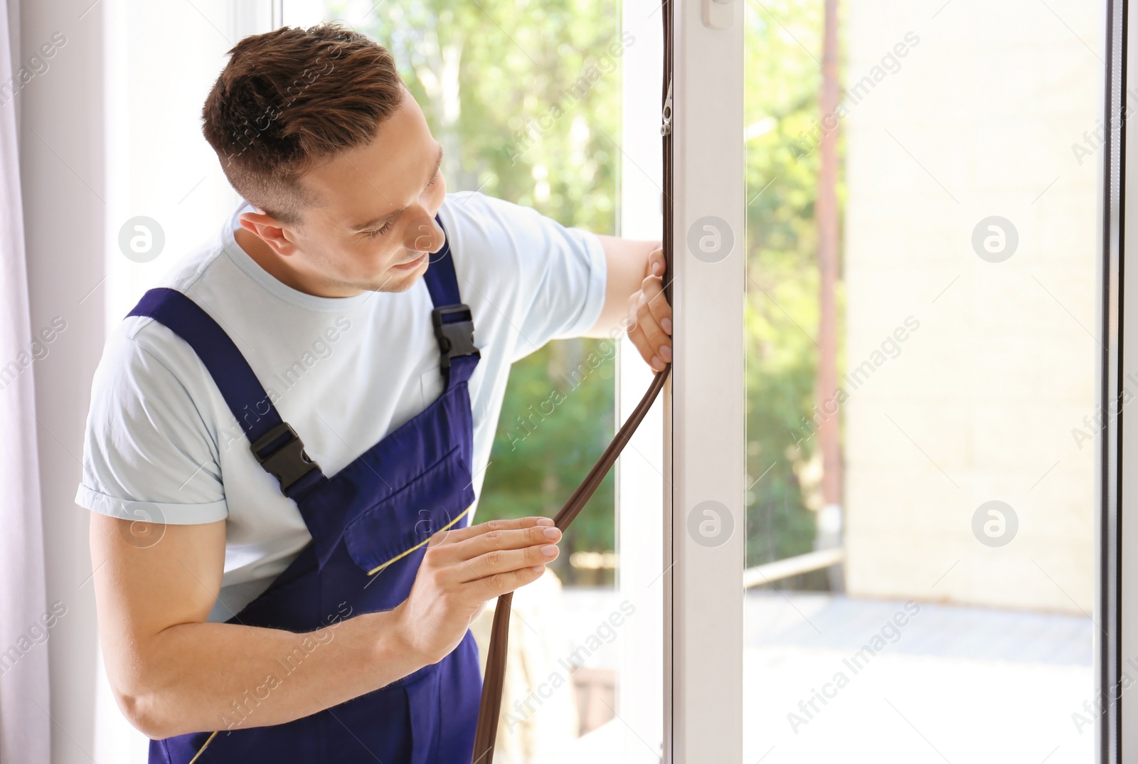 Photo of Construction worker putting sealing foam tape on window indoors