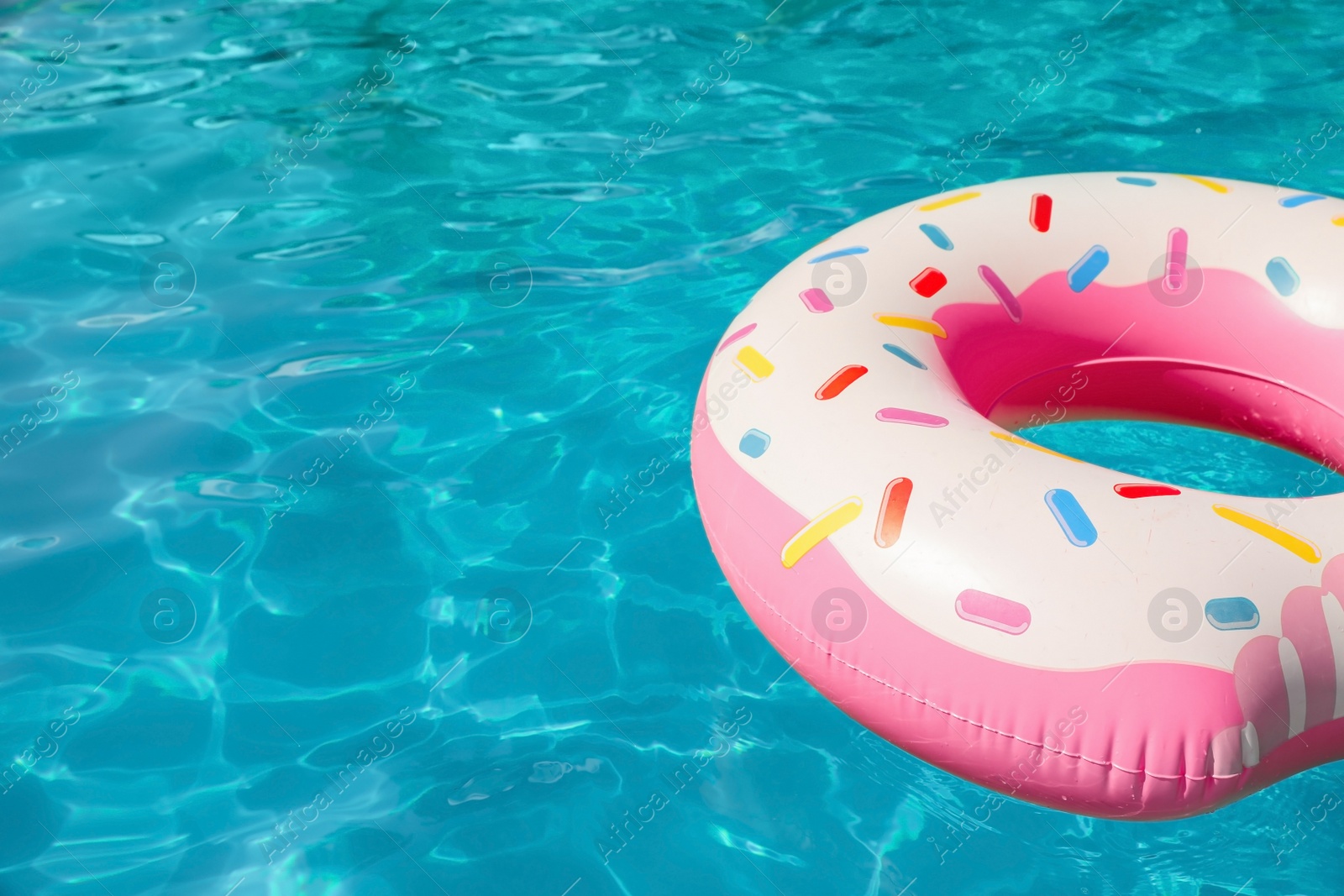 Photo of Inflatable ring floating in swimming pool on sunny day. Space for text