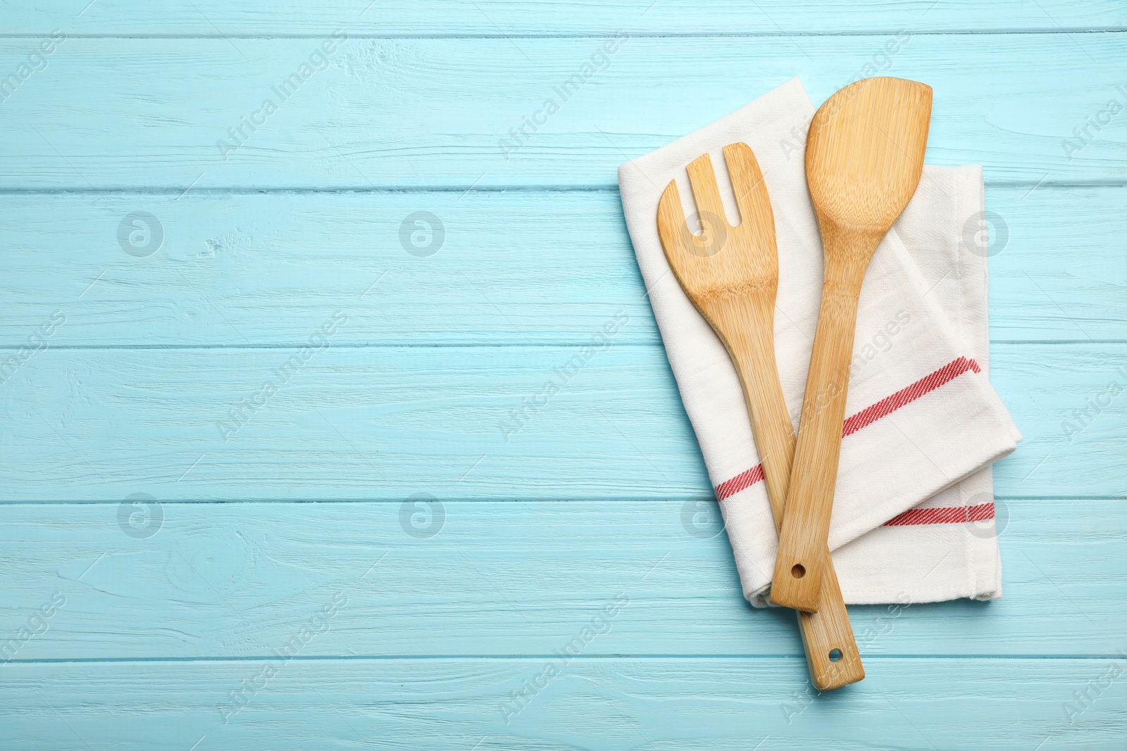 Photo of Wooden spatula, fork and napkin on color background, top view with space for text