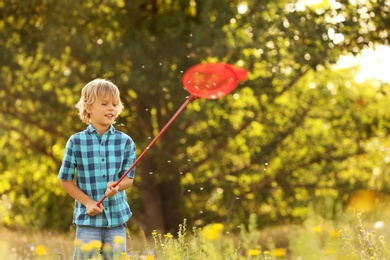 Photo of Cute little boy with butterfly net outdoors. Child spending time in nature