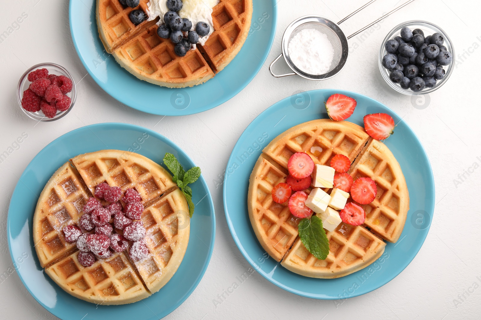 Photo of Tasty Belgian waffles with fresh berries served on white table, flat lay