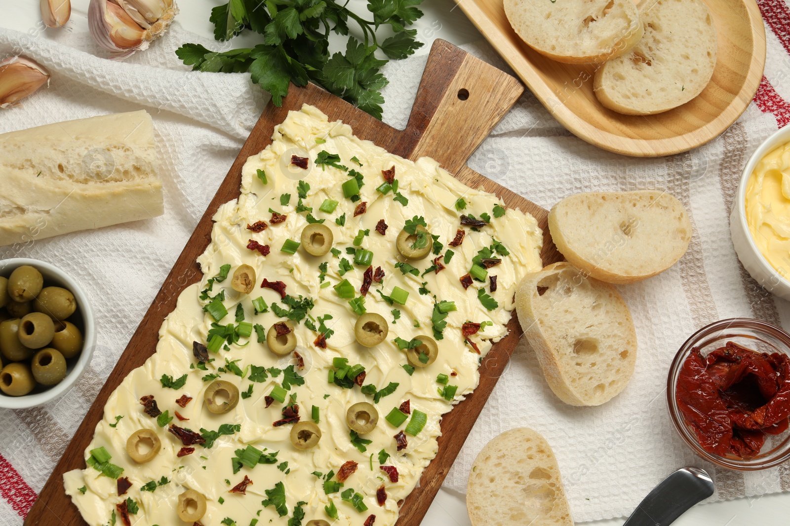 Photo of Fresh butter board with olives, sun-dried tomatoes and bread on table, flat lay