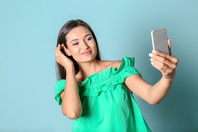 Photo of Young beautiful woman taking selfie against color background