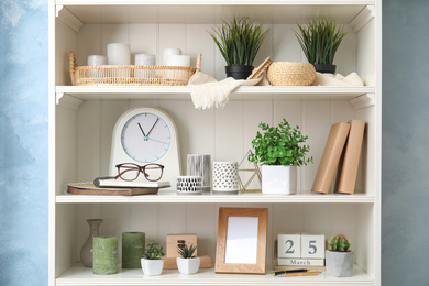 Photo of White shelving unit with plants and different decorative stuff