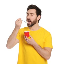 Photo of Handsome man eating delicious yogurt on white background