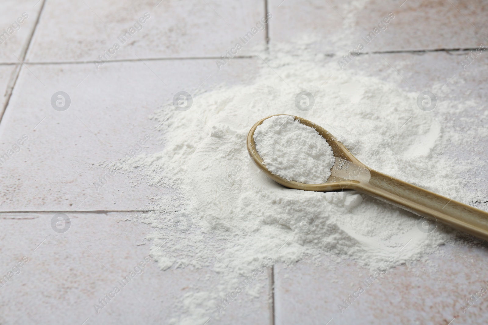 Photo of Pile of baking powder and spoon on light tiled table, closeup. Space for text