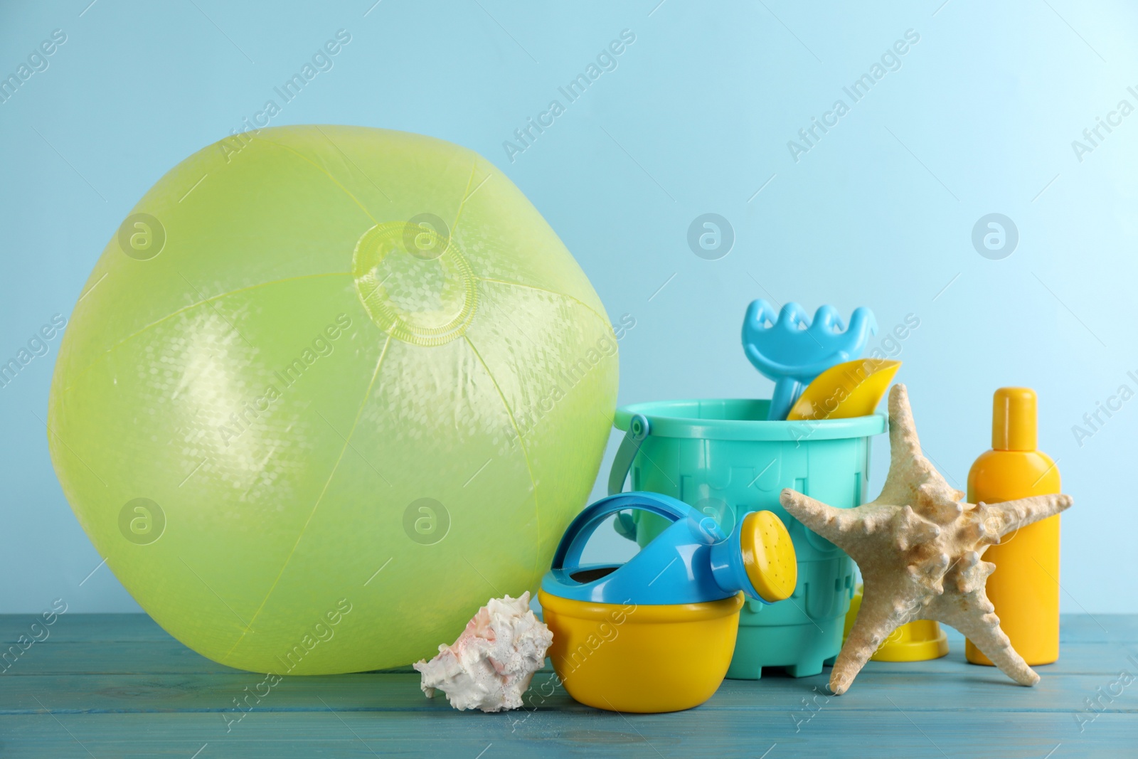 Photo of Beach ball and sand toys on light blue wooden table