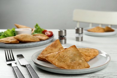 Photo of Fresh delicious crispy samosas served on white  wooden table