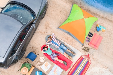 Image of Couple with camping equipment near car on sand, aerial view. Summer trip