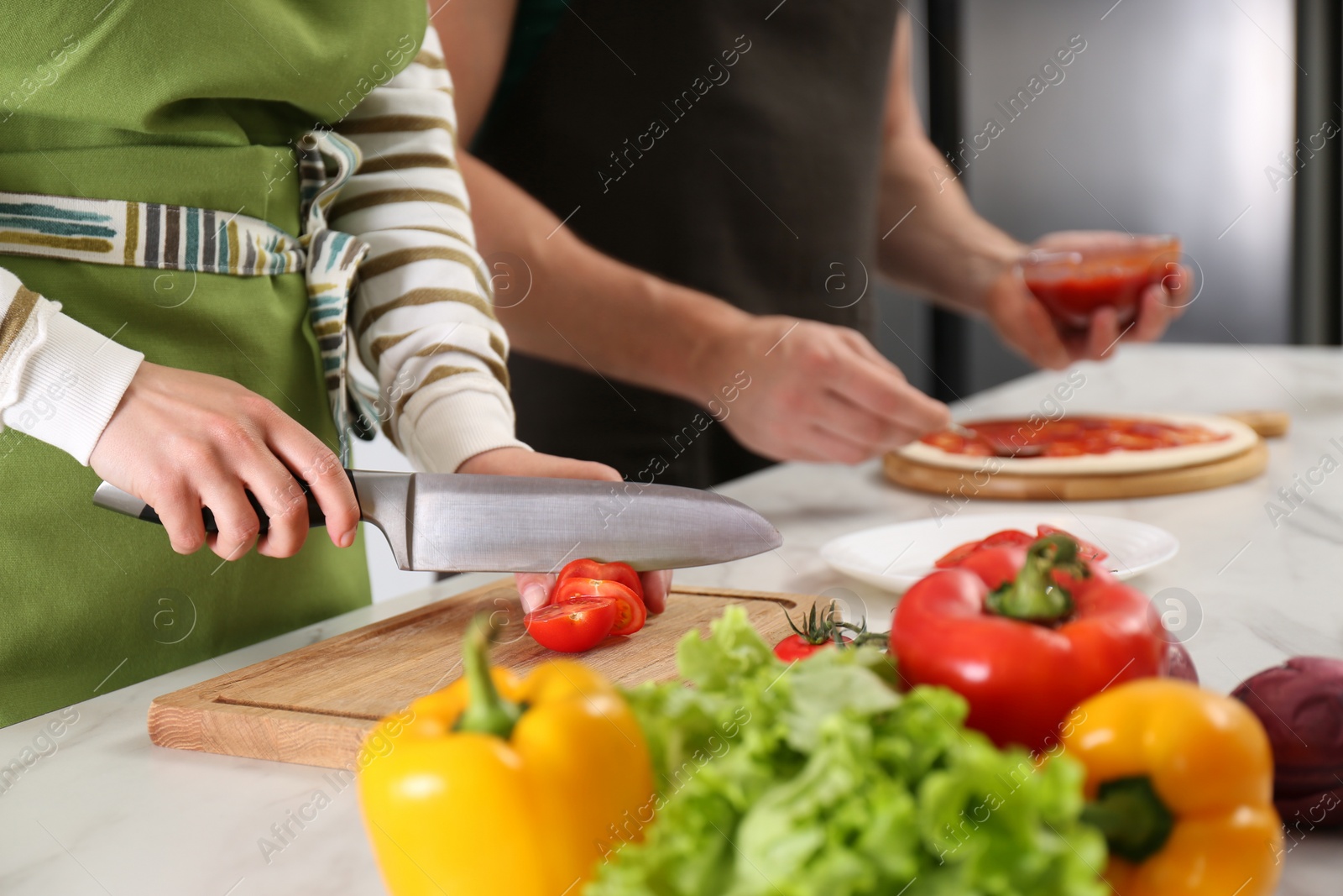 Photo of Couple making pizza in kitchen, closeup. Cooking together