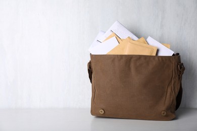 Photo of Postman's bag full of letters and newspapers on white wooden background. Space for text