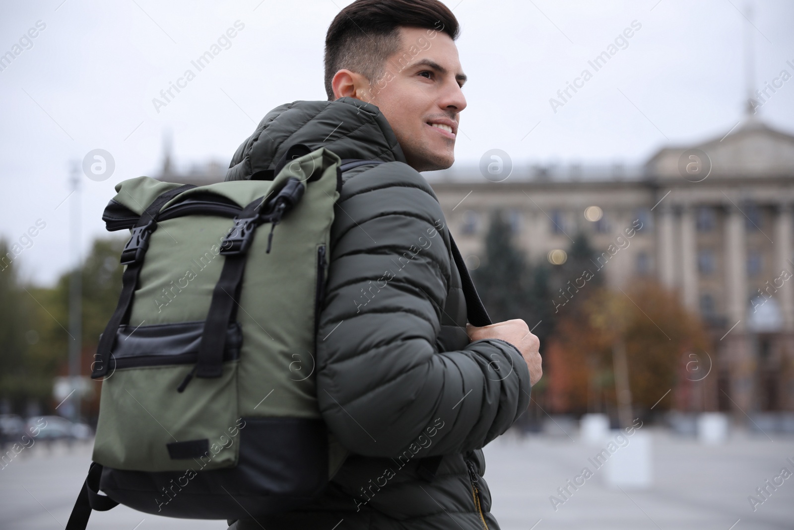 Photo of Male tourist with travel backpack on city street. Urban trip