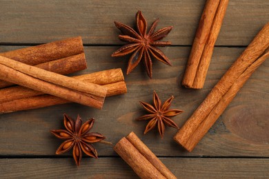 Photo of Cinnamon sticks and star anise on wooden table, flat lay