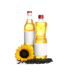 Photo of Bottles of sunflower cooking oil, seeds and yellow flower on white background