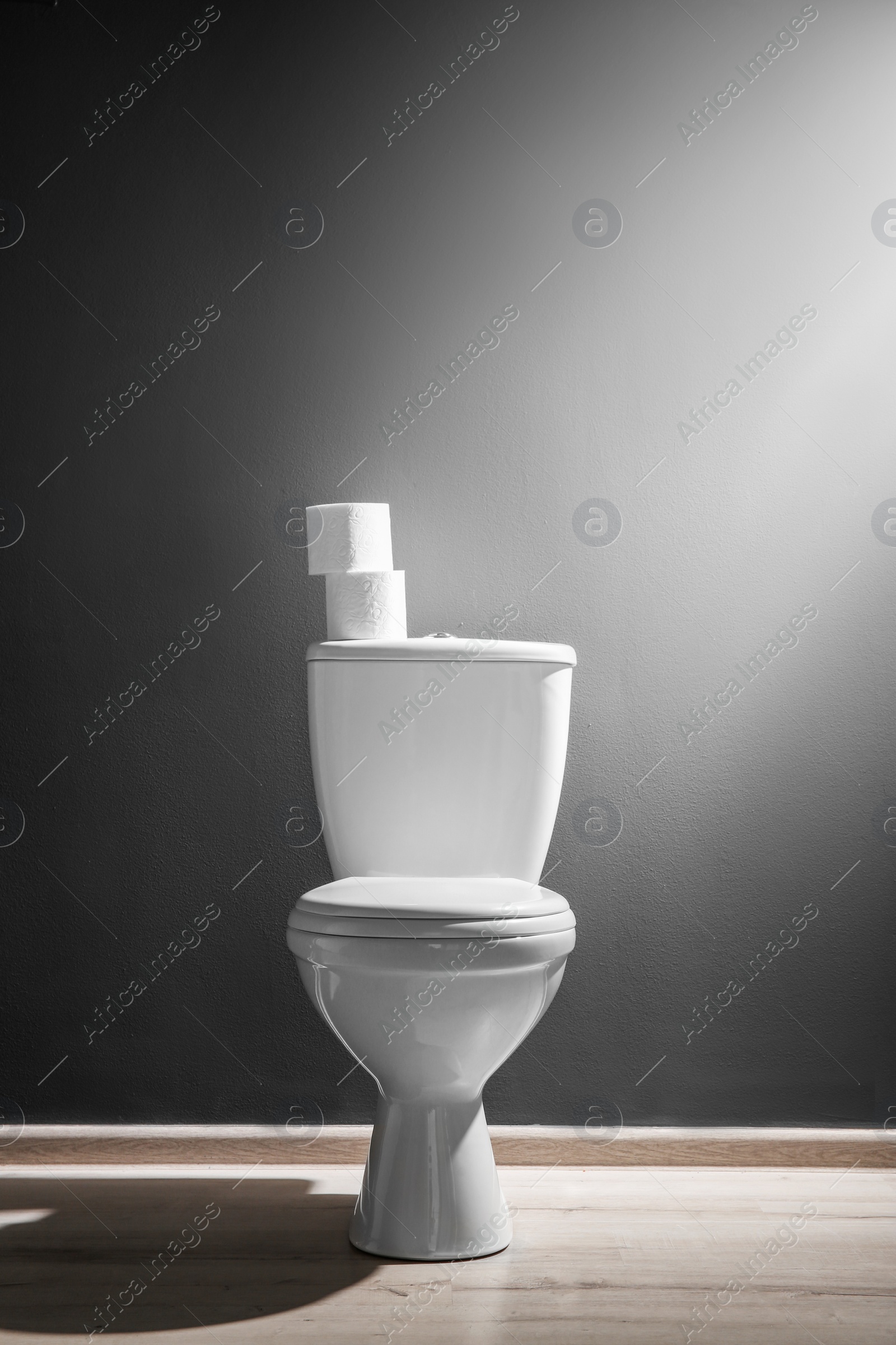 Photo of New ceramic toilet bowl near grey wall, side light