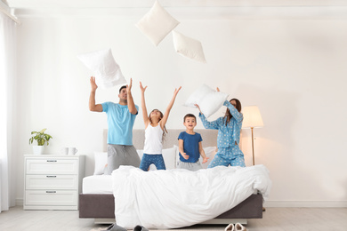 Photo of Happy family playing with pillows in bedroom