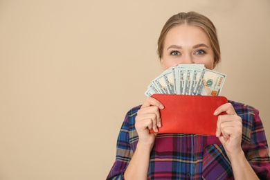 Photo of Happy young woman with wallet full of money on color background. Space for text
