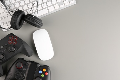 Photo of Gamepads, mouse and headphones on gray background