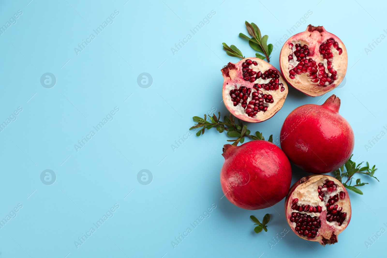 Photo of Flat lay composition with ripe pomegranates on light blue background. Space for text