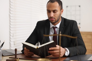 Serious lawyer reading book at table in office