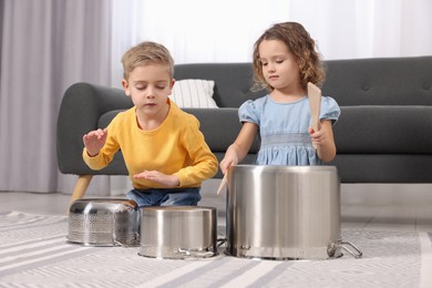 Little children pretending to play drums on pots at home