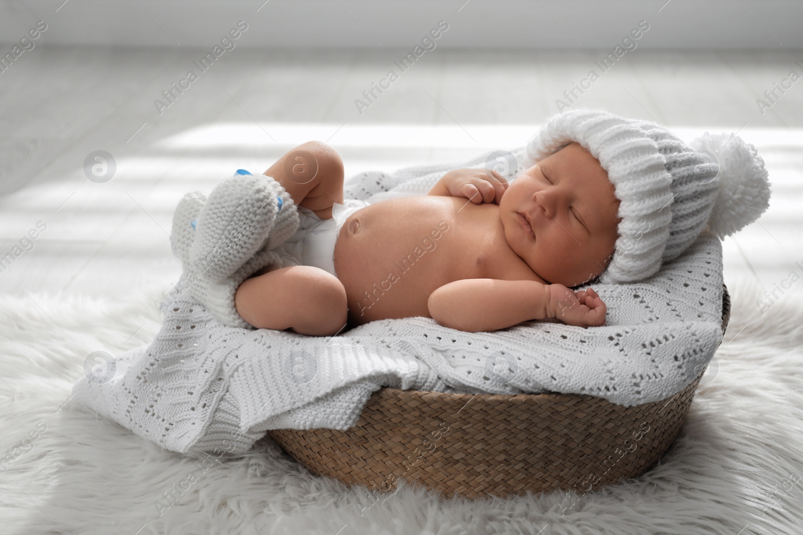 Photo of Cute newborn baby wearing warm hat and socks sleeping in wicker basket