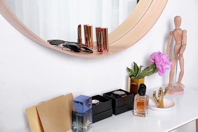 Photo of Stylish round mirror and dressing table with accessories indoors. Interior design