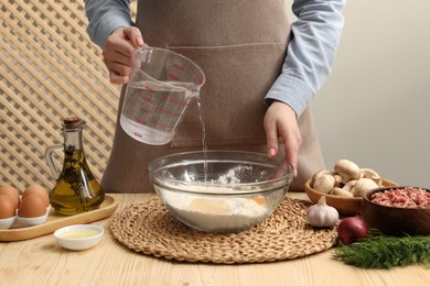 Woman making dough at wooden table, closeup