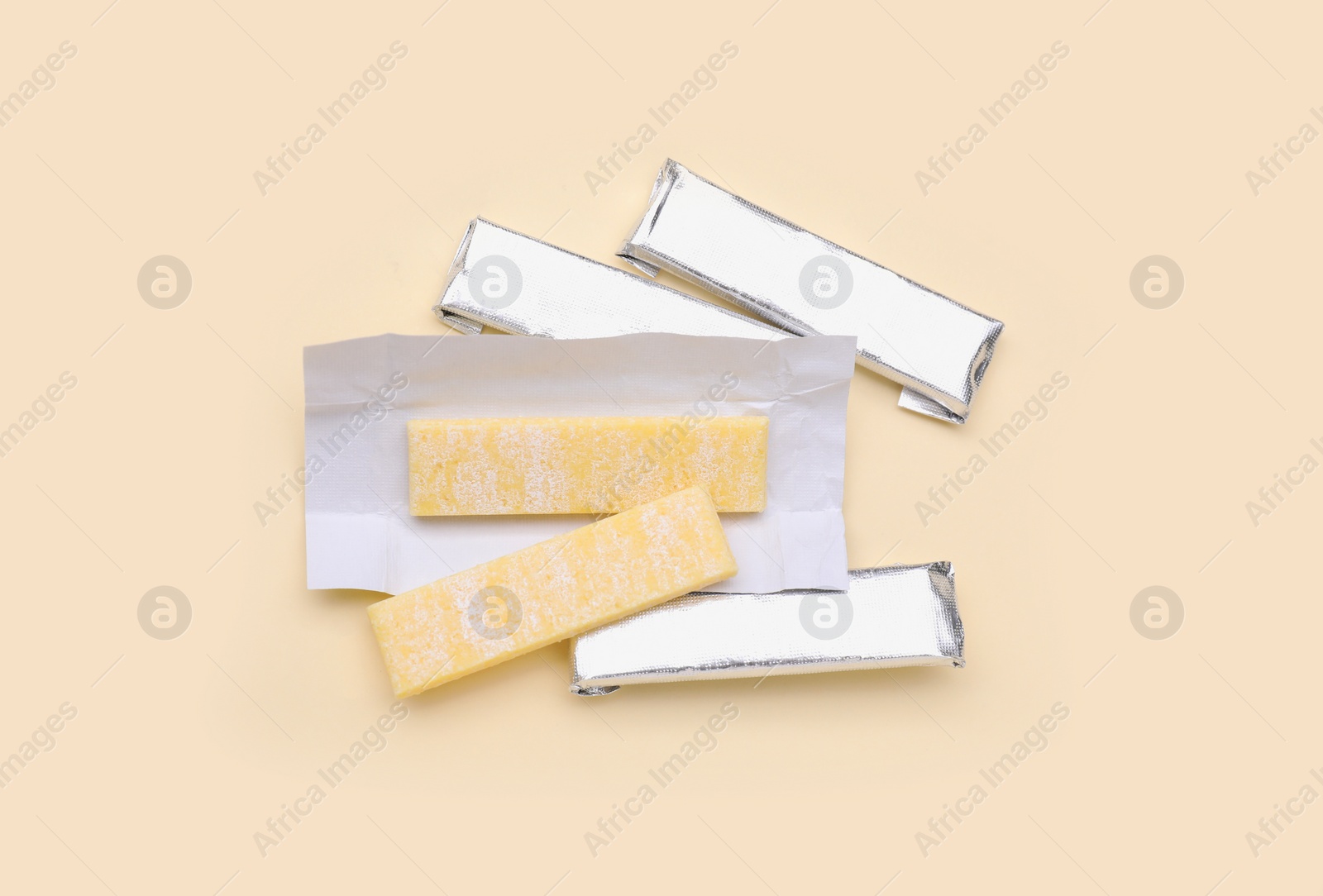 Photo of Sticks of tasty chewing gum on beige background, flat lay