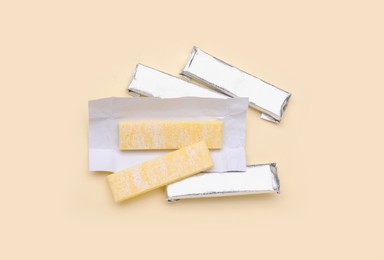 Photo of Sticks of tasty chewing gum on beige background, flat lay