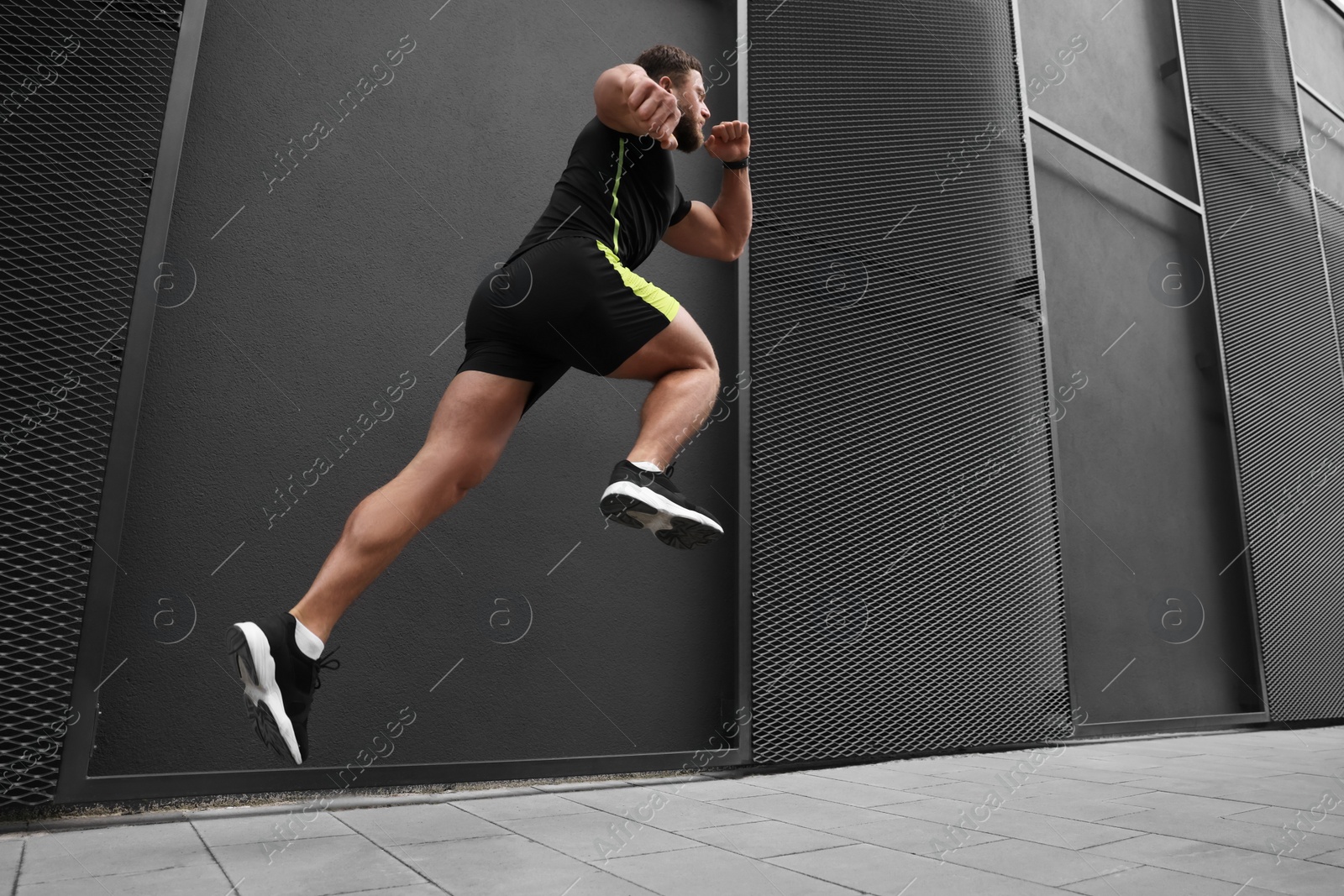Photo of Man running near building outdoors, low angle view. Space for text
