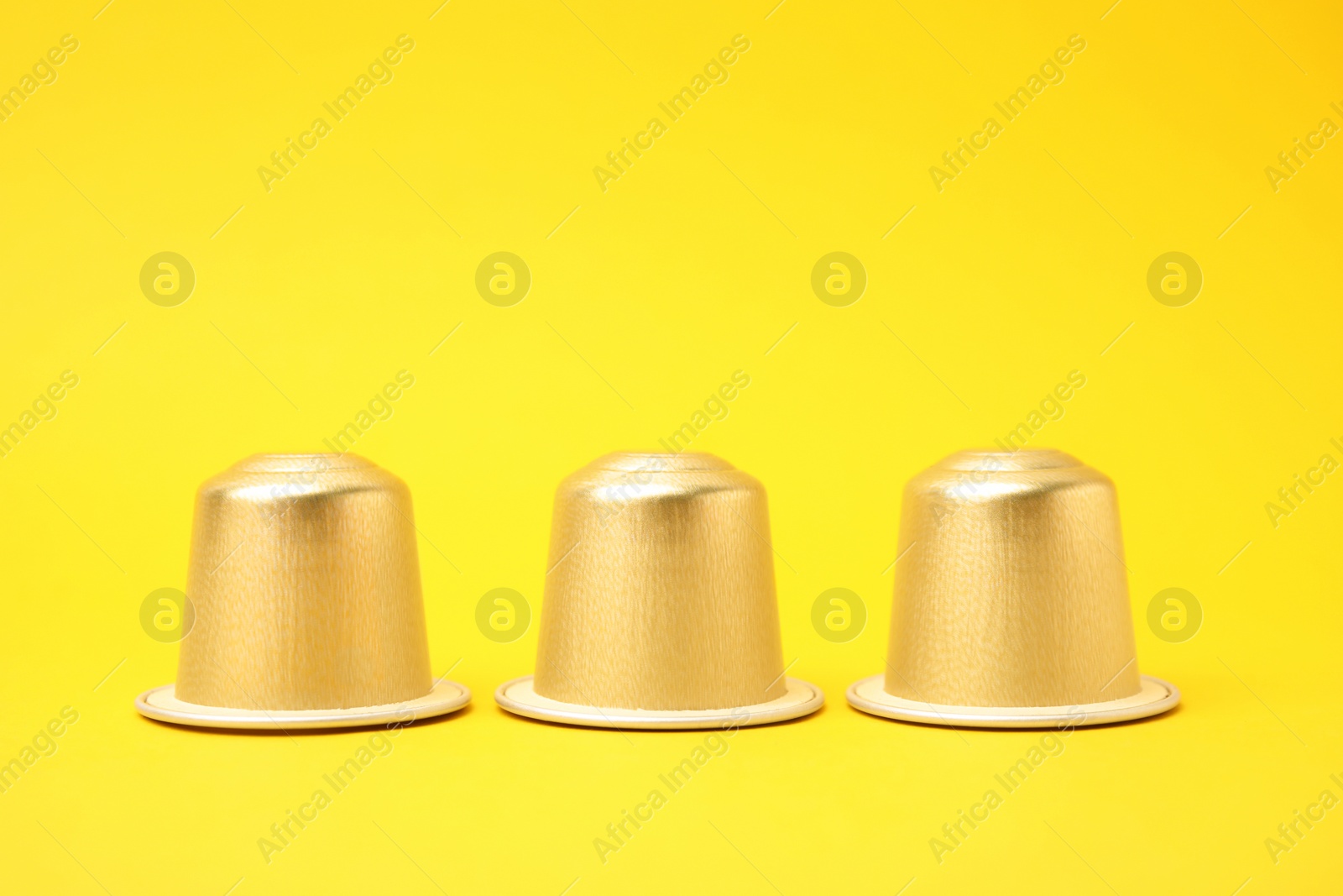 Photo of Three plastic coffee capsules on yellow background
