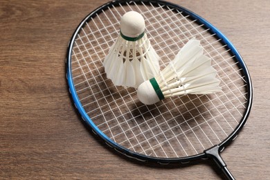 Photo of Feather badminton shuttlecocks and racket on wooden table, closeup