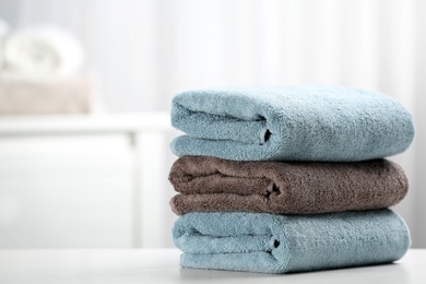 Photo of Stack of fresh towels on table. Space for text