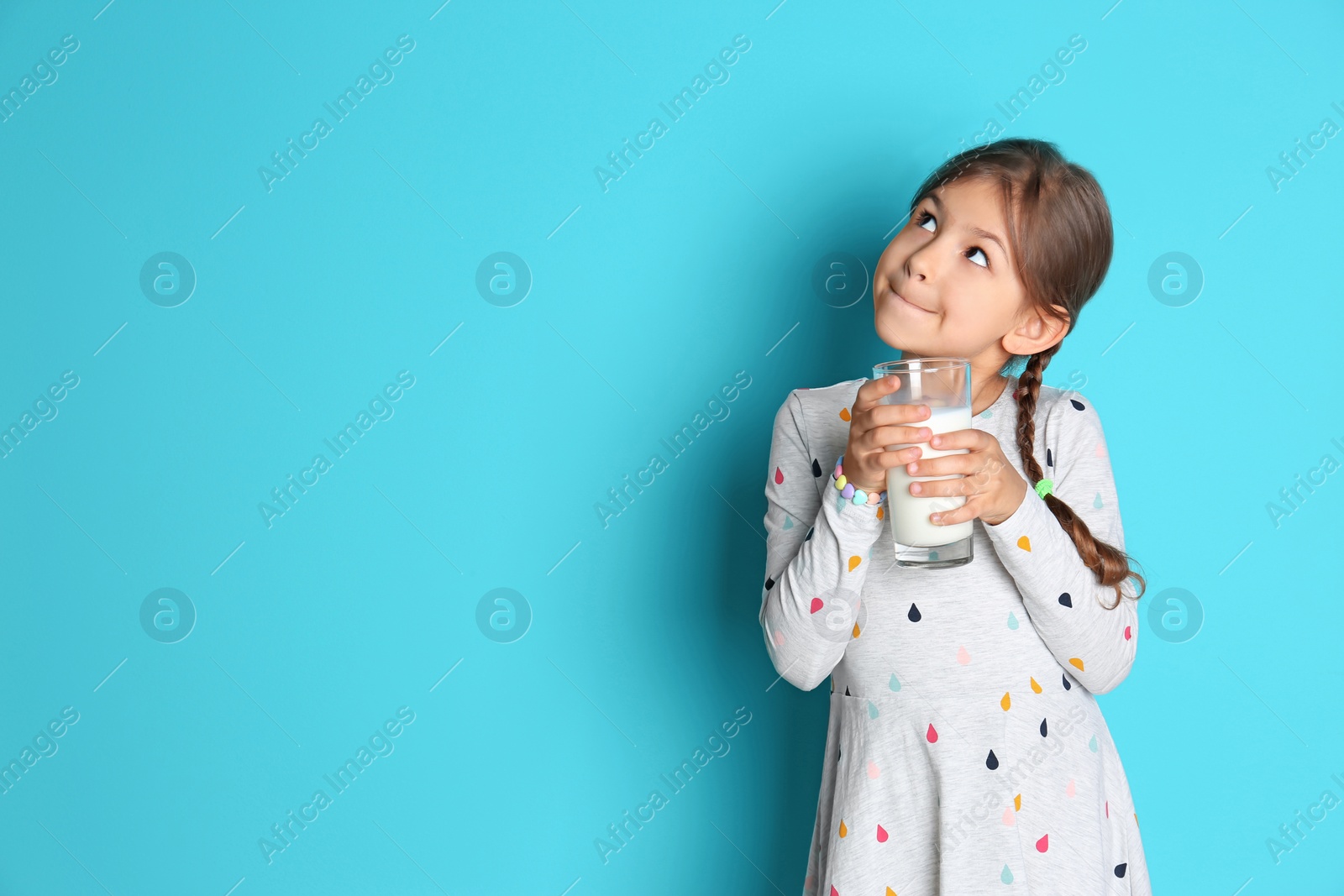 Photo of Cute little girl with glass of milk on color background