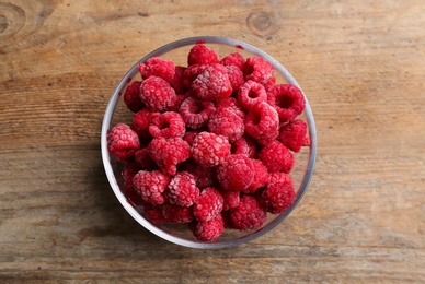 Tasty frozen raspberries on wooden table, top view