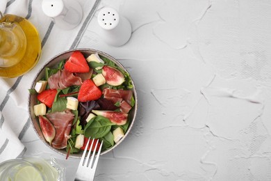 Photo of Tasty salad with brie cheese, prosciutto, strawberries and figs on white textured table, flat lay. Space for text