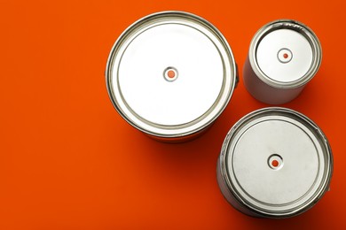Photo of Cans of orange paint on color background, top view. Space for text