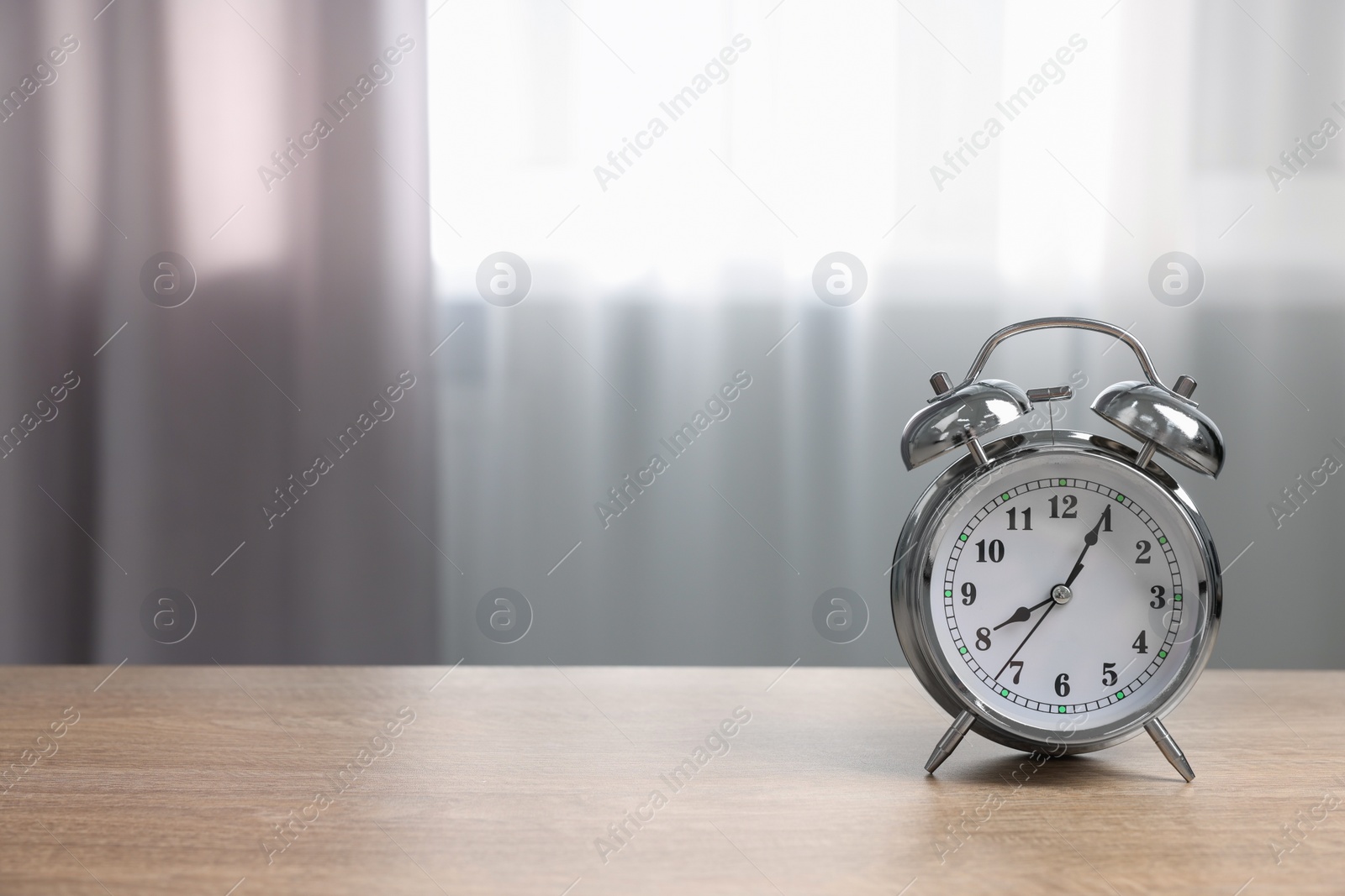 Photo of Silver alarm clock on wooden table indoors, space for text