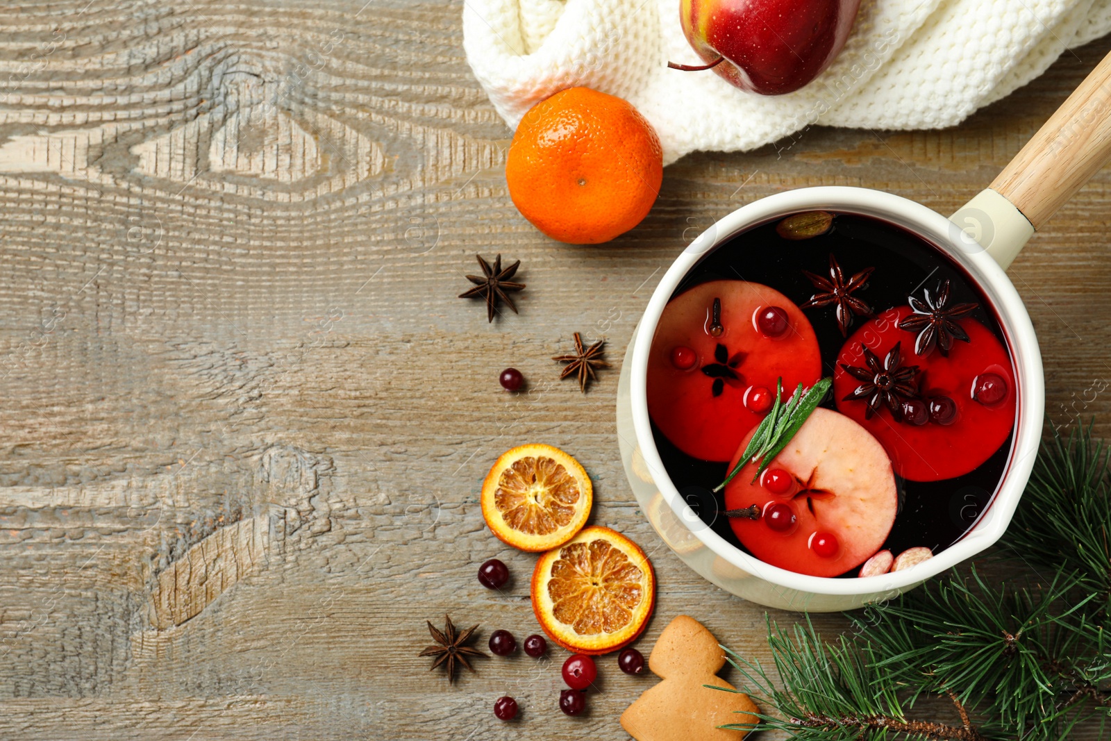 Photo of Saucepan with tasty mulled wine on wooden background, flat lay. Space for text