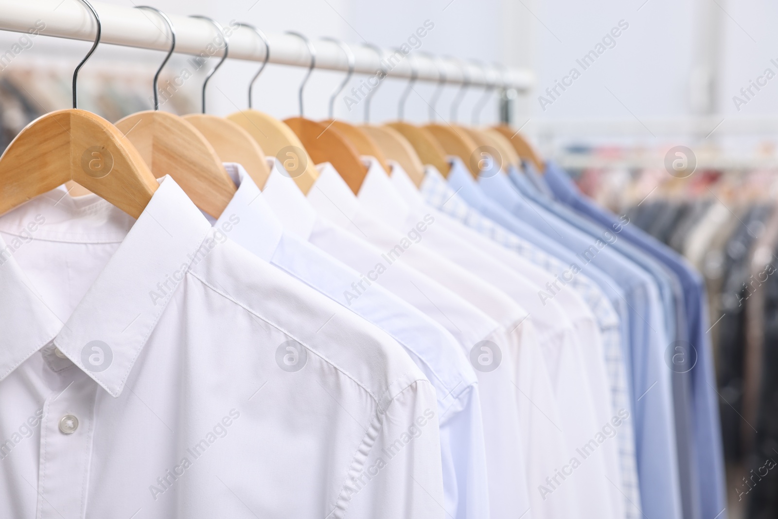 Photo of Dry-cleaning service. Many different clothes hanging on rack indoors, closeup