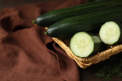 Fresh cucumbers in wicker basket on table, closeup. Space for text